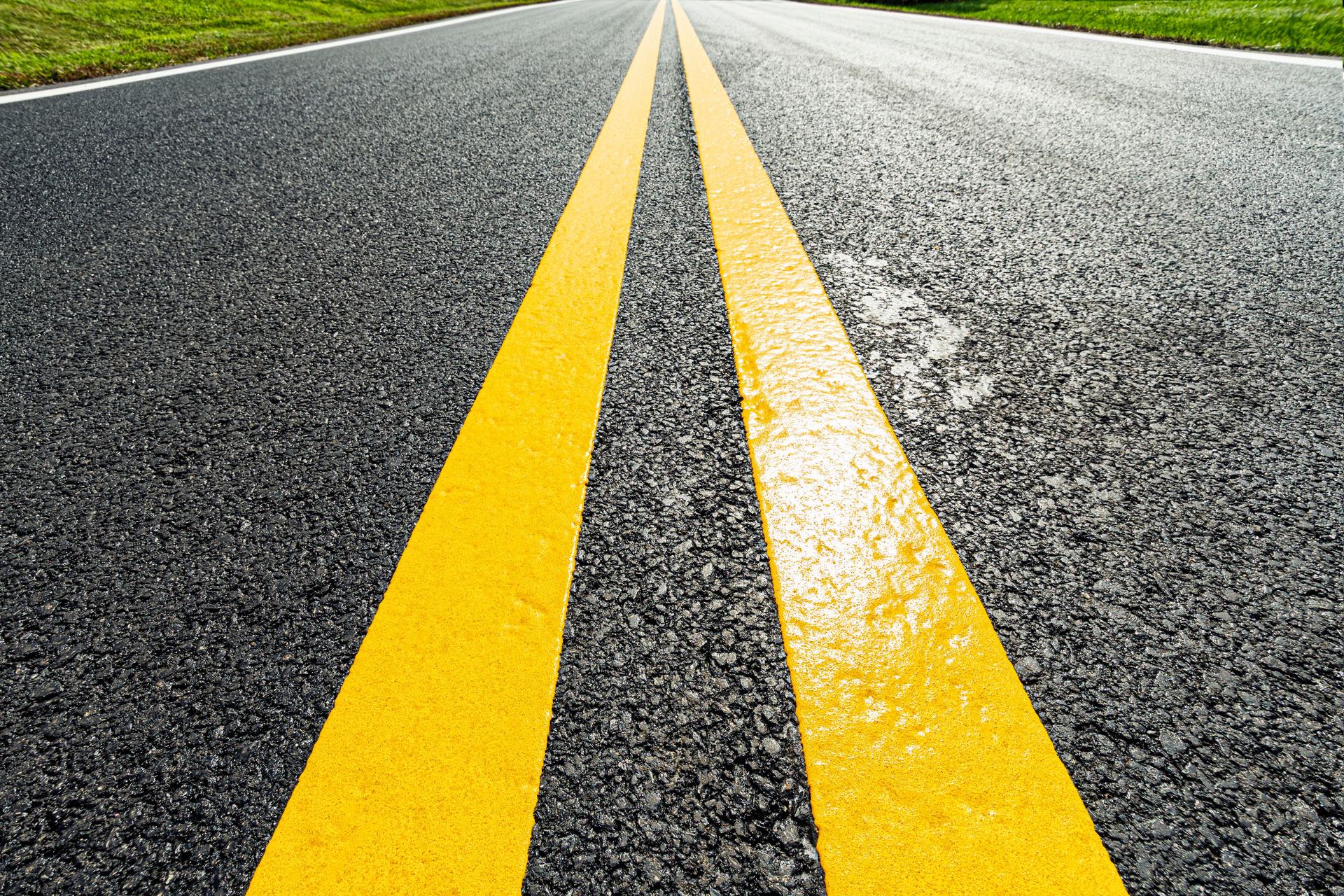 Low angle view of a freshly painted double yellow lines on a newly paved road
