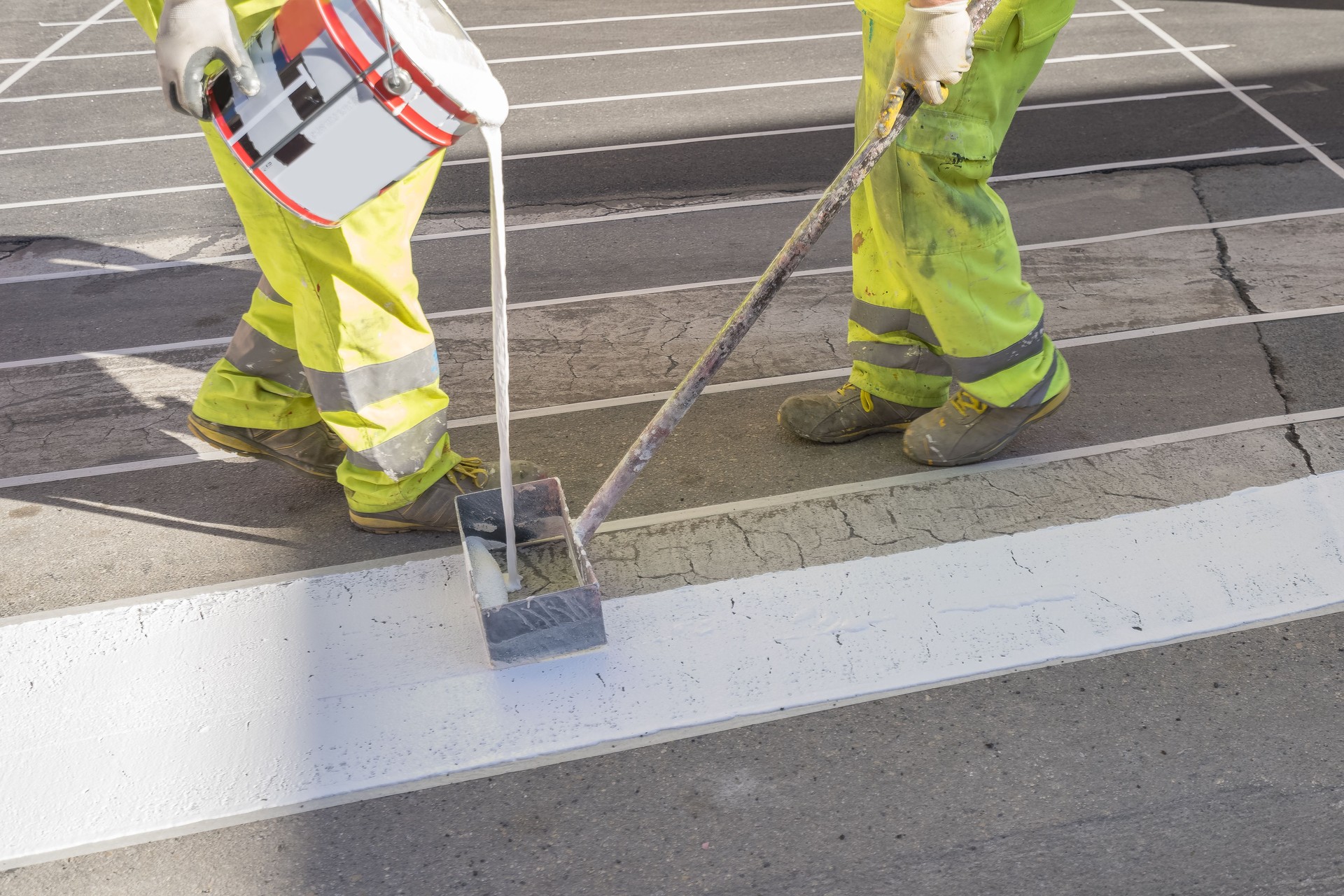 Unrecognizable maintenance workers painting the road